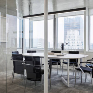 Empty chairs around table in board room. Modern meeting room against window in office. Furniture seen through glass walls in conference room.