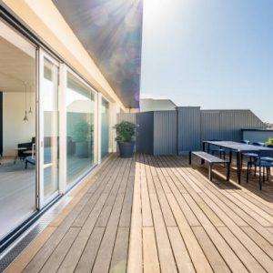 Hardwood rooftop patio deck with a picknick table and chairs. Floor to ceiling sliding doors open up to the loft apartment.